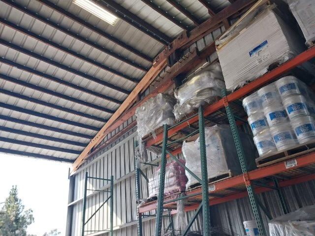 Failing warehouse roof beam visible above racked product, structural hazard