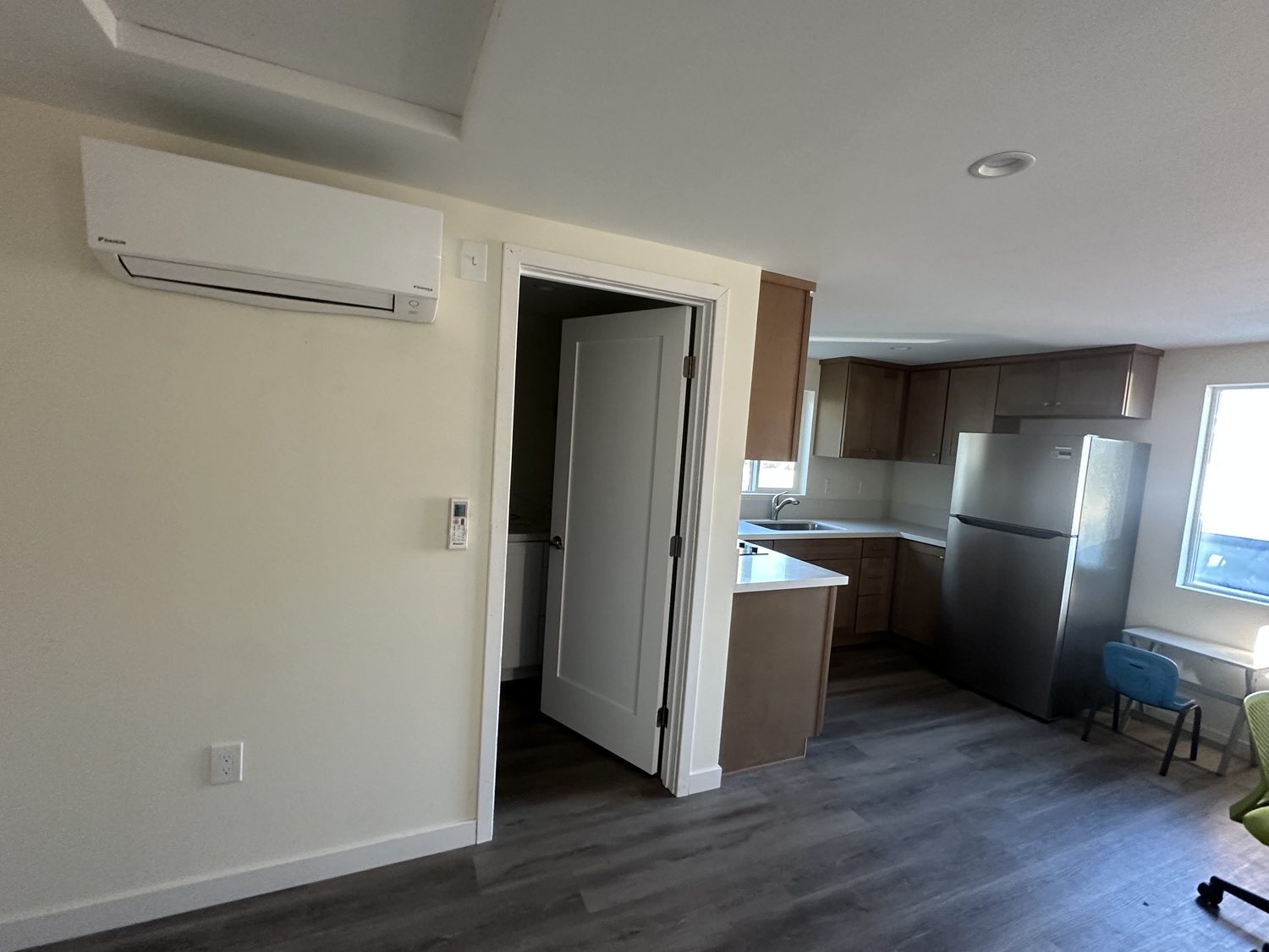 Main room with a wall-mounted mini-split, plank floors and the kitchen beyond