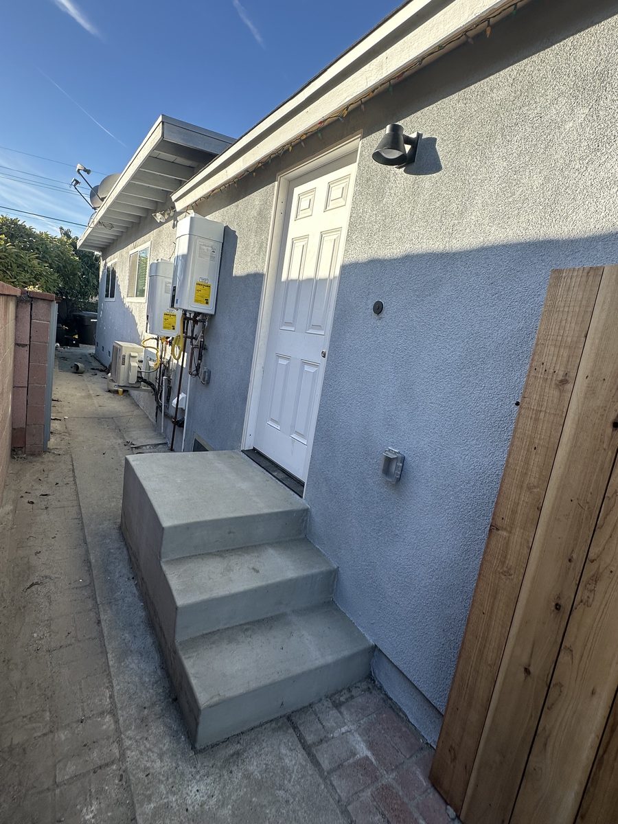 Concrete steps up to the side entry door in the finished stucco wall