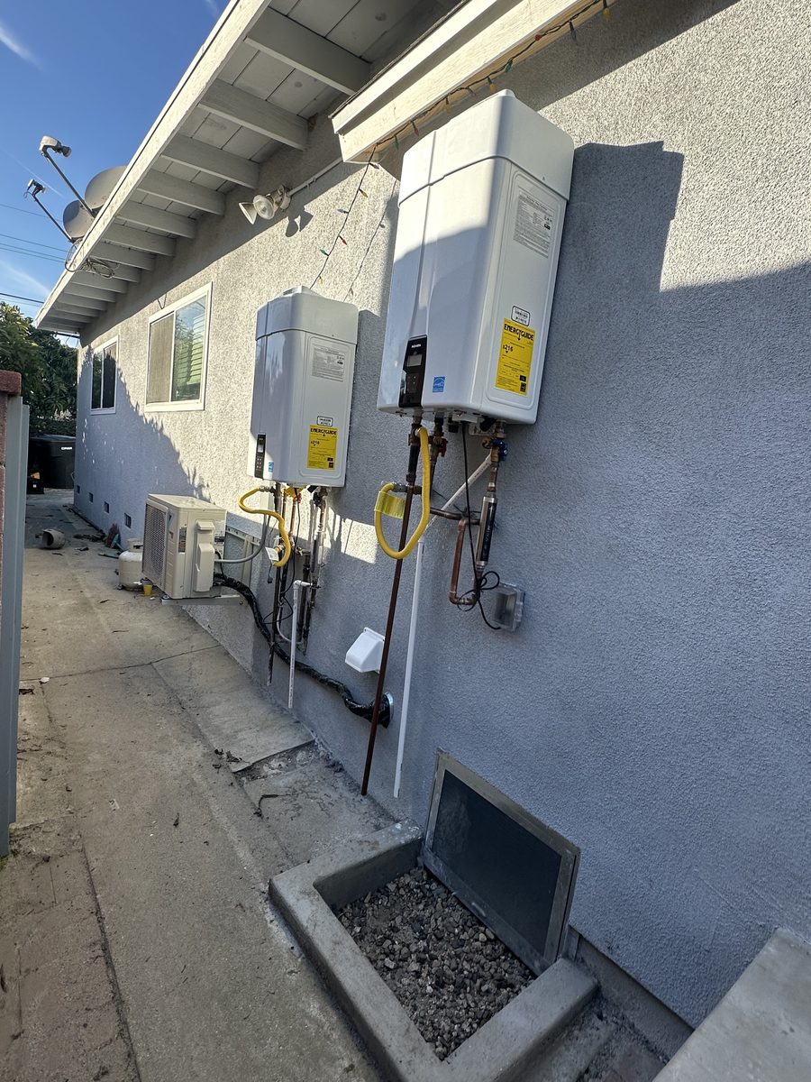 Finished stucco wall along the side yard, with wall-mounted water heaters and a mini-split condenser