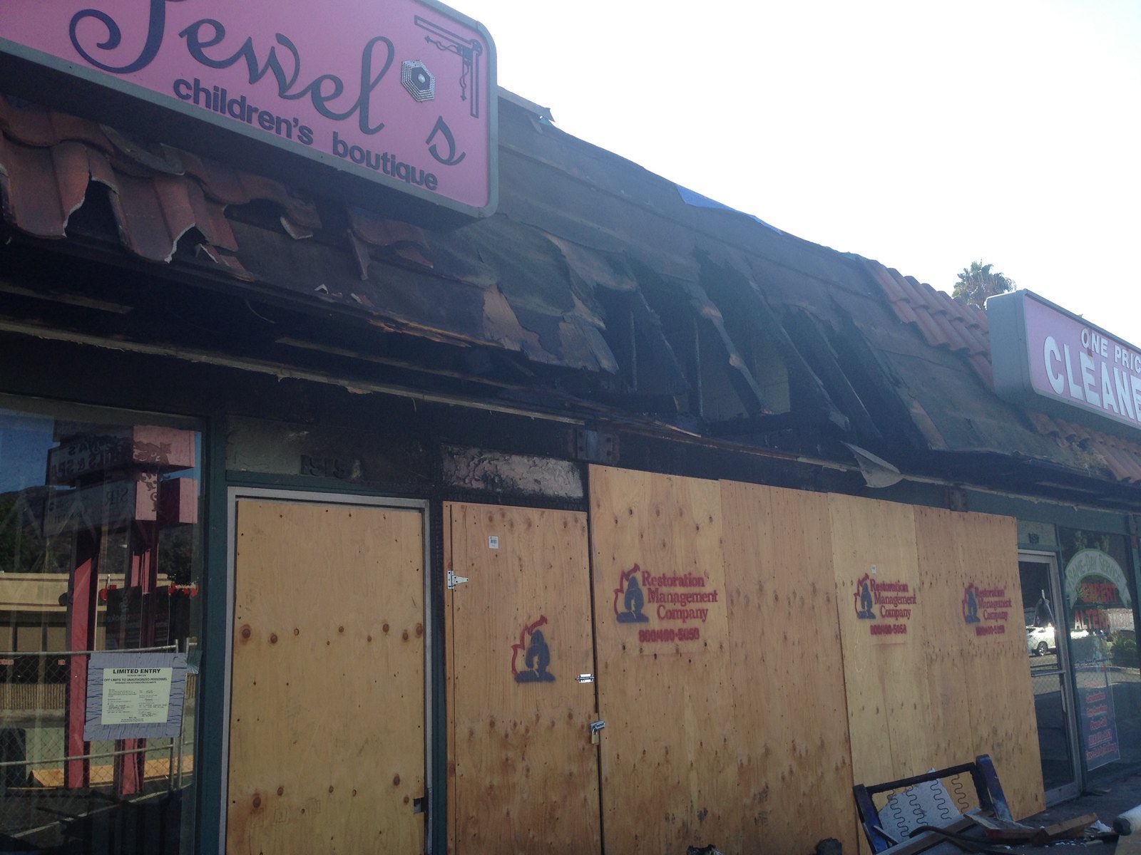 Fire-damaged storefronts boarded over with plywood, scorched signage above