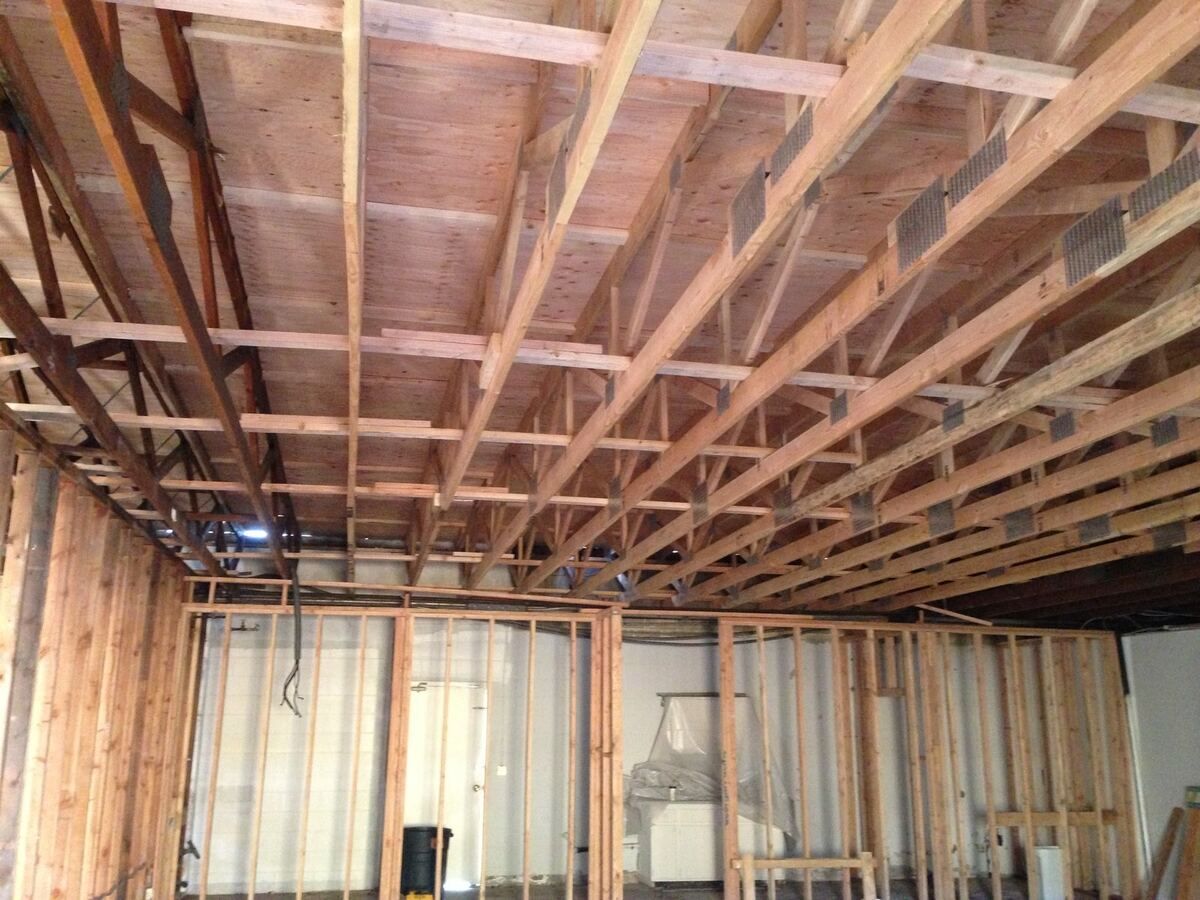 New roof framing seen from below, fresh joists and blocking in place