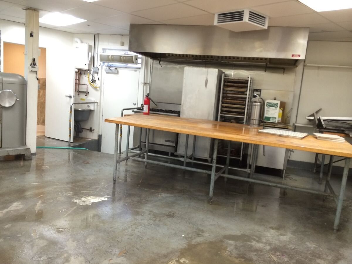 Finished commercial kitchen in a tenant suite with stainless prep tables and a bakery oven