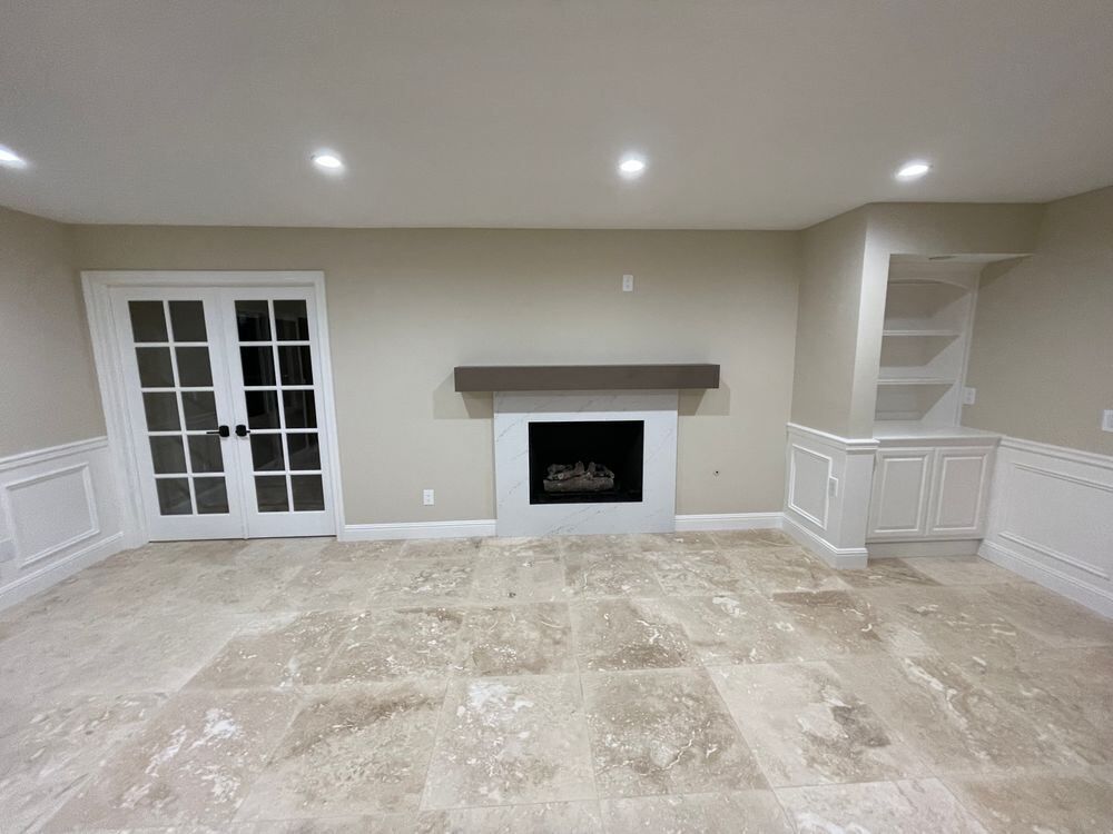 Finished living room with fireplace, French doors and built-in shelving