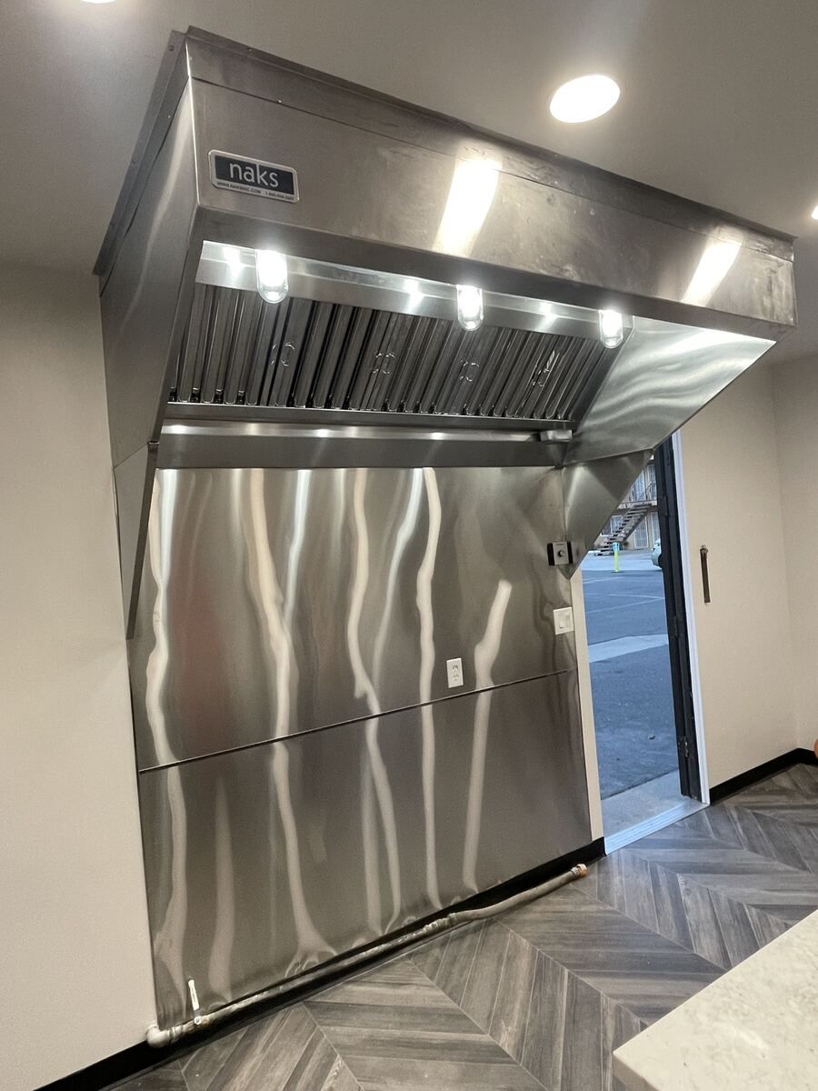 Stainless commercial exhaust hood installed over the cook line
