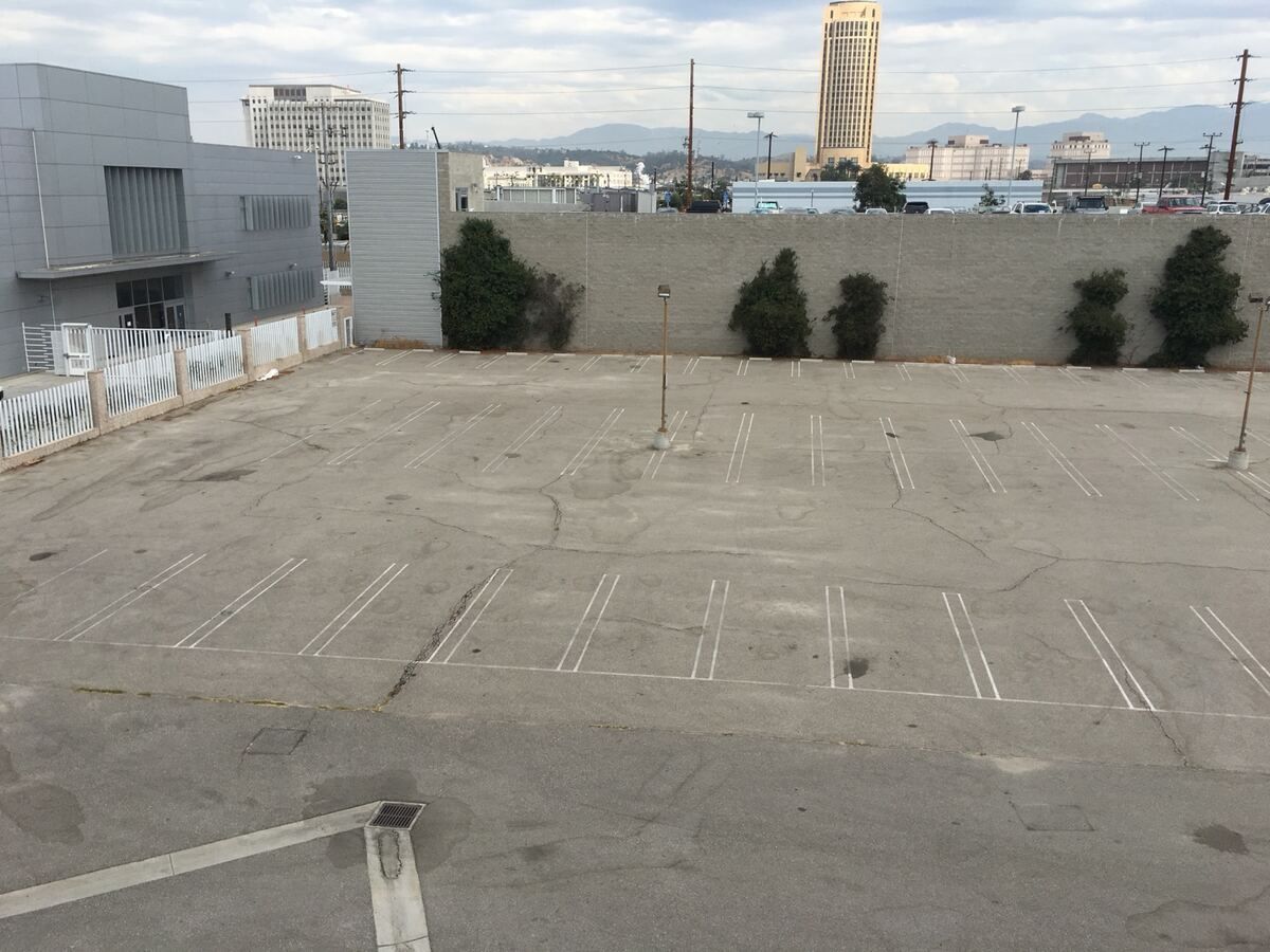 Worn grey parking lot with cracked asphalt and faded striping before seal coating