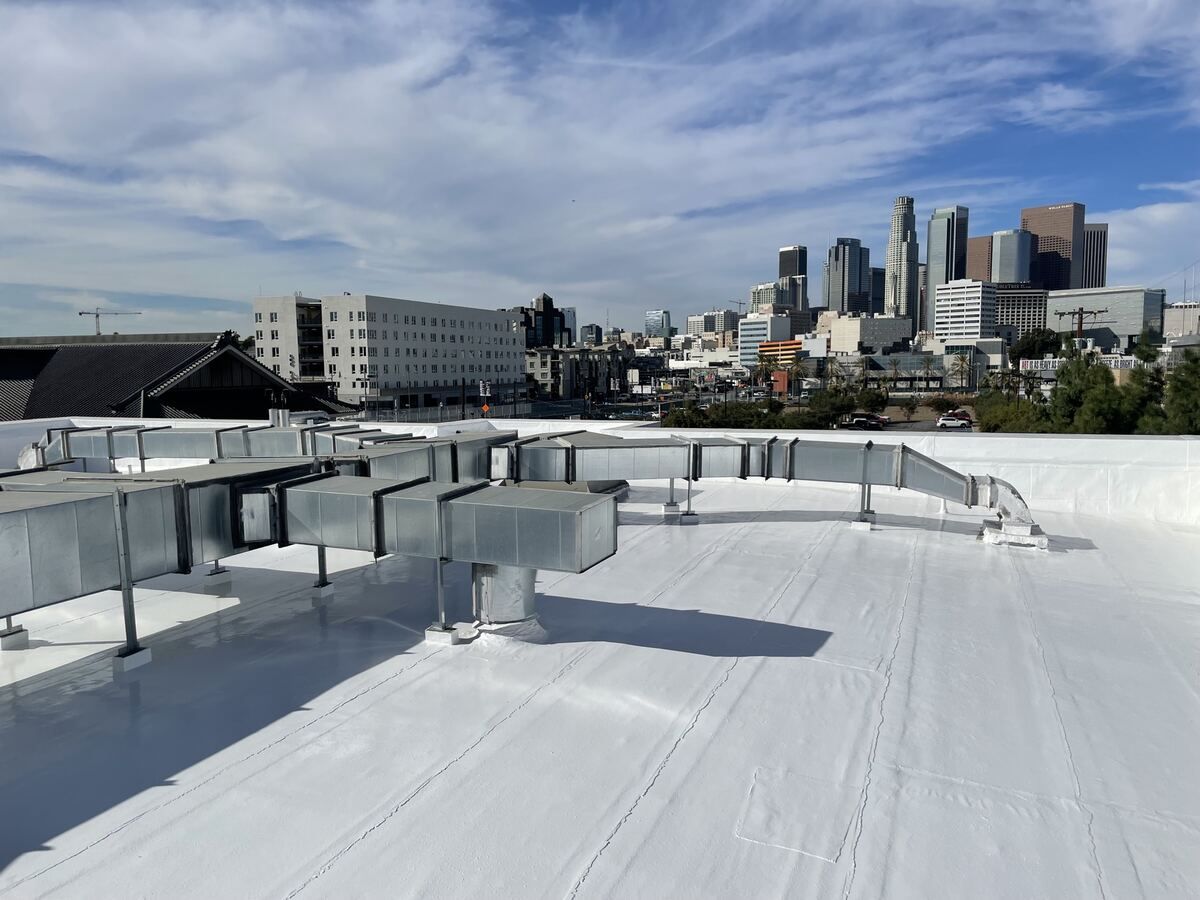 Finished white-coated flat roof with the new ductwork in place, temple tile roof at left and the downtown Los Angeles skyline behind