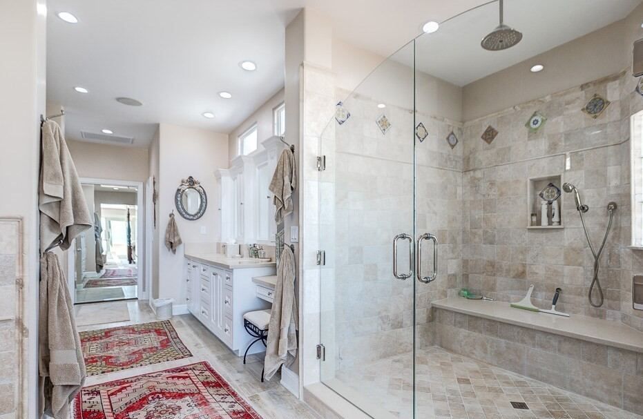 Primary bath in travertine with a freestanding tub and a glass shower enclosure