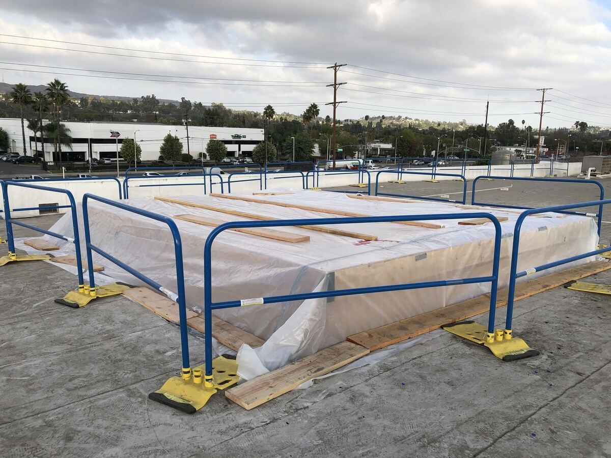 Blue safety rail set around the roof opening with new timber staged alongside