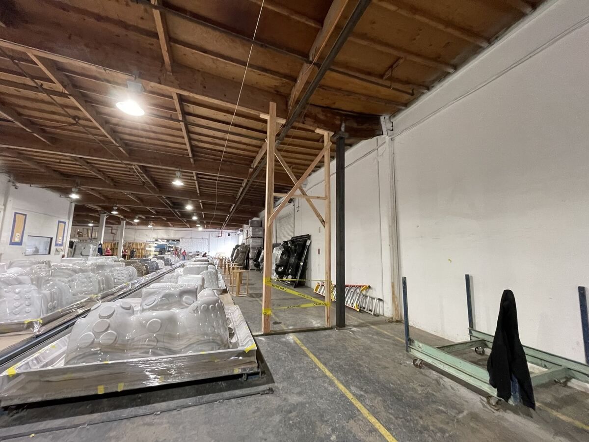 Shoring posts inside a taped-off work zone with the rest of the warehouse floor still in use