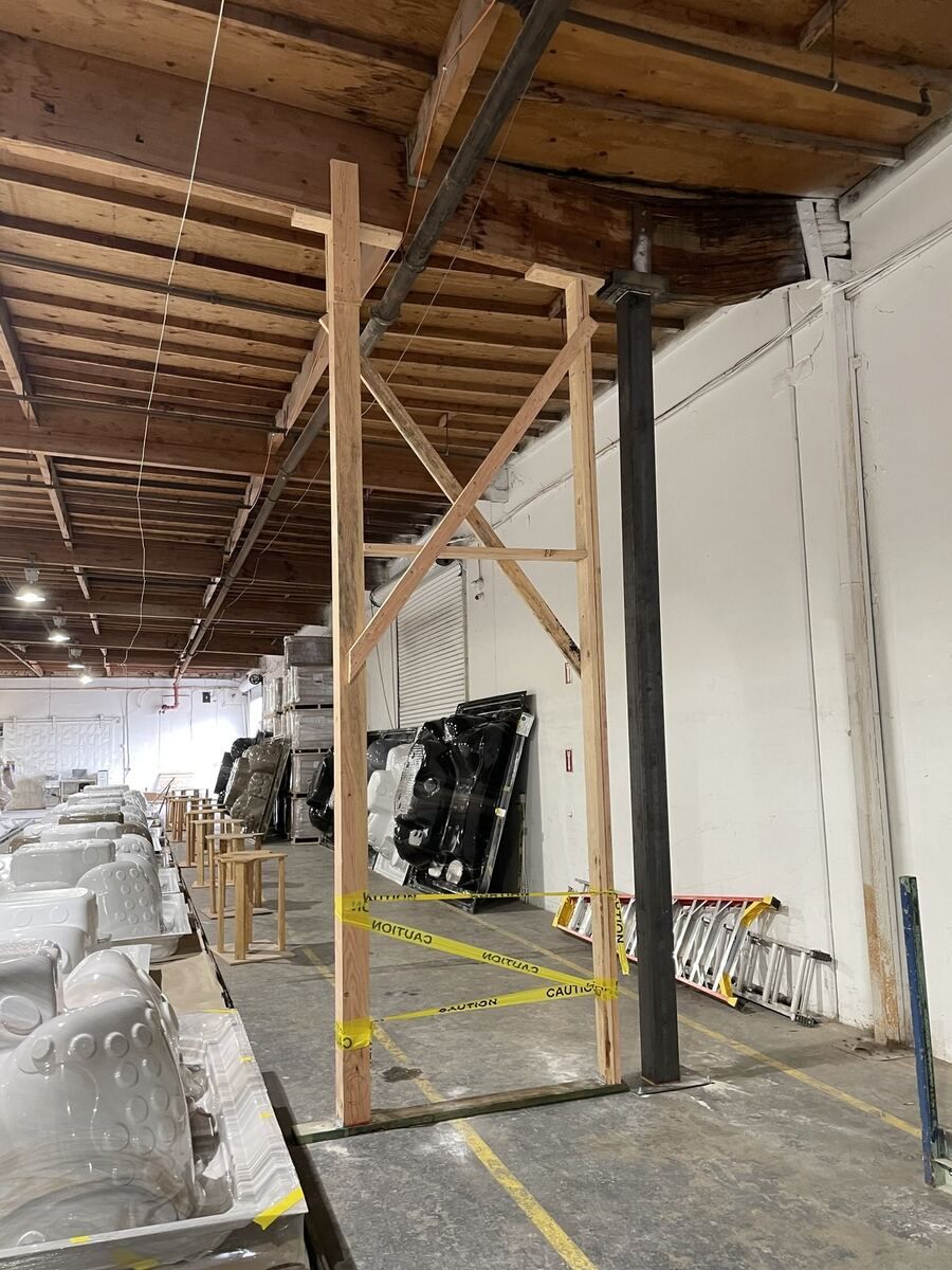 Temporary timber shoring posts carrying a warehouse roof over racked and wrapped product