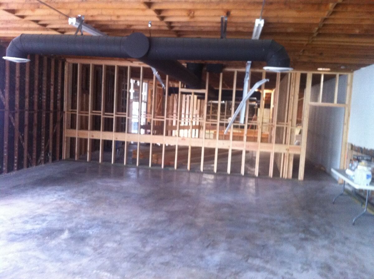 Interior mid-build with new wood stud partition walls framed under an open wood joist ceiling and a large insulated duct run overhead